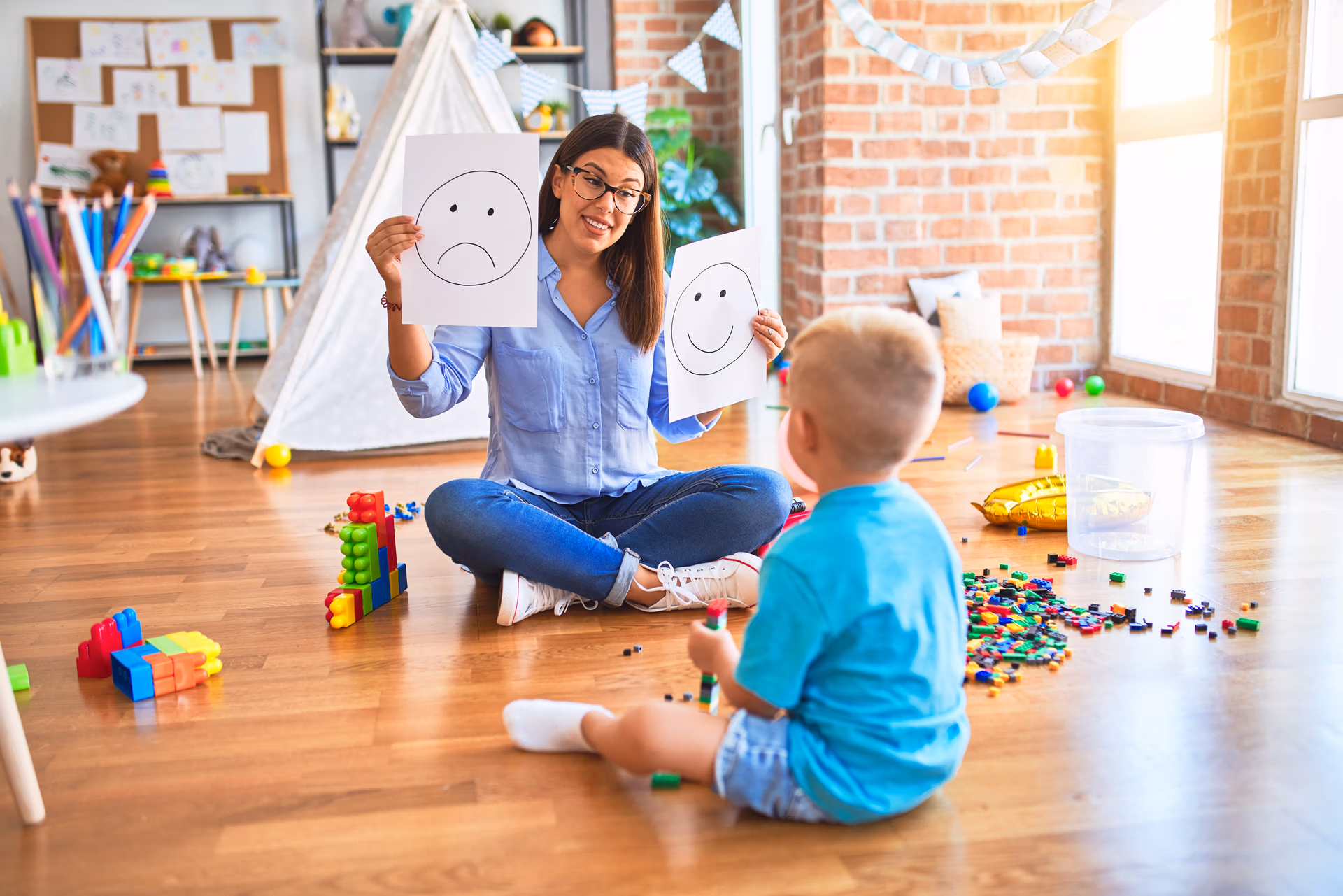young therapist woman speaking with child, counselor and behaviour correction at the office showing happy and sad face
